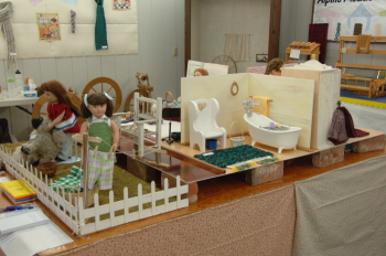 Picket fence around lawn of doll house.