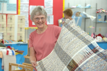 Weaver holding up rug.