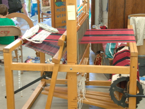 Rug loom with red and black warp.