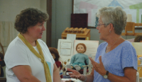 Two women talking at fair booth.