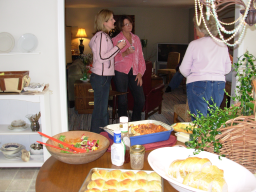 Table with food and people standing talking.